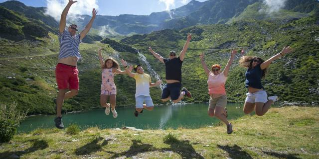 famille sautant de joie aux 7 Laux en été devant un lac